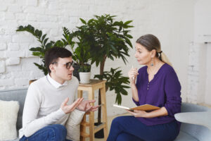 Jovem conversando com terapeuta em ambiente acolhedor, representando apoio emocional para estudantes.