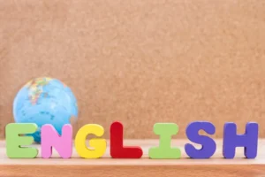 Letras coloridas formando a palavra "ENGLISH" com um globo ao fundo, representando Aulas de ESL (Inglês como Segunda Língua).
