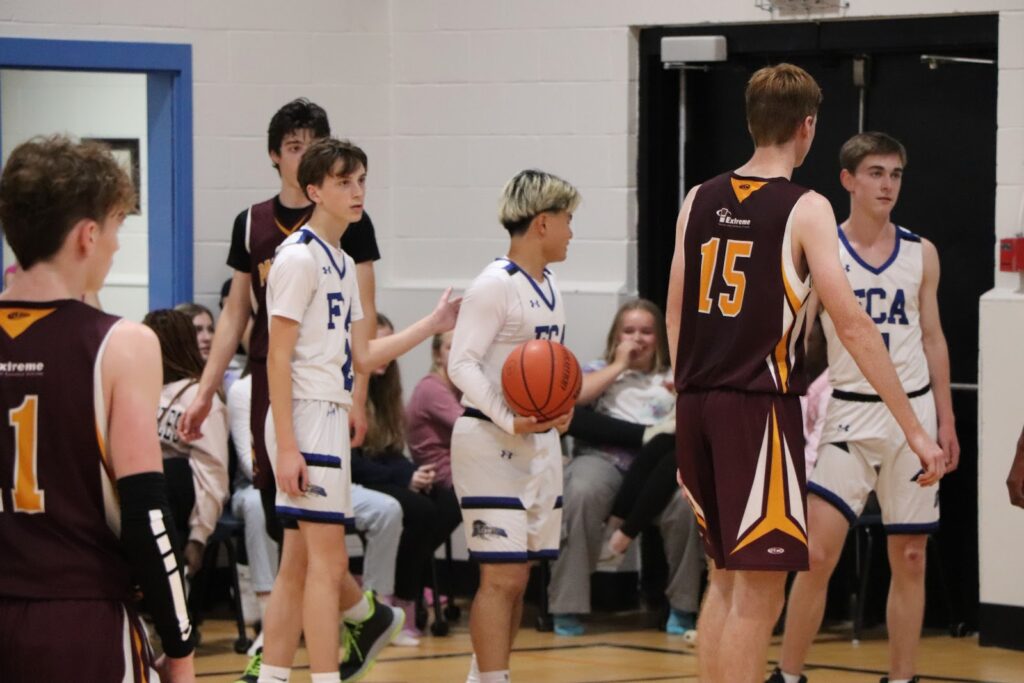 Alunos da Fredericton Christian Academy participando de jogo de basquetebol, promovendo esportes e trabalho em equipe.
