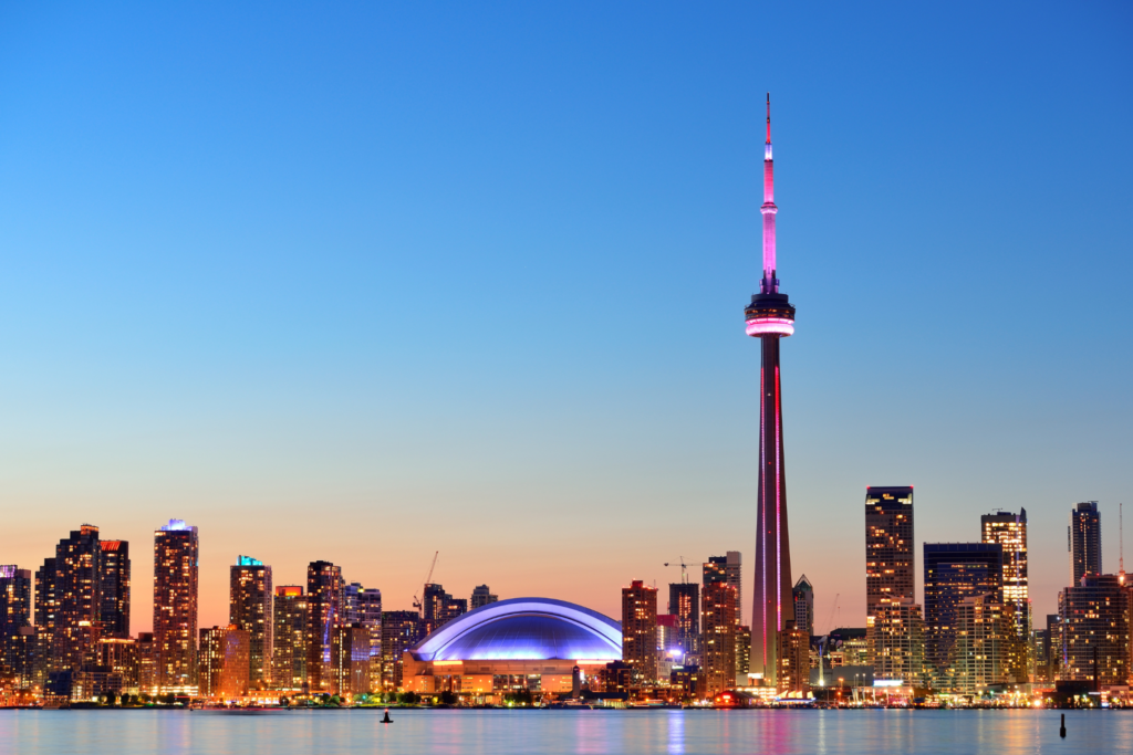 Vista noturna da skyline de Toronto com a CN Tower iluminada, um dos pontos turísticos mais icônicos do Canadá.