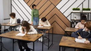 Estudiantes en aula escribiendo bajo la supervisión de una maestra, representando el Currículo K-12 en una escuela cristiana de Fredericton.