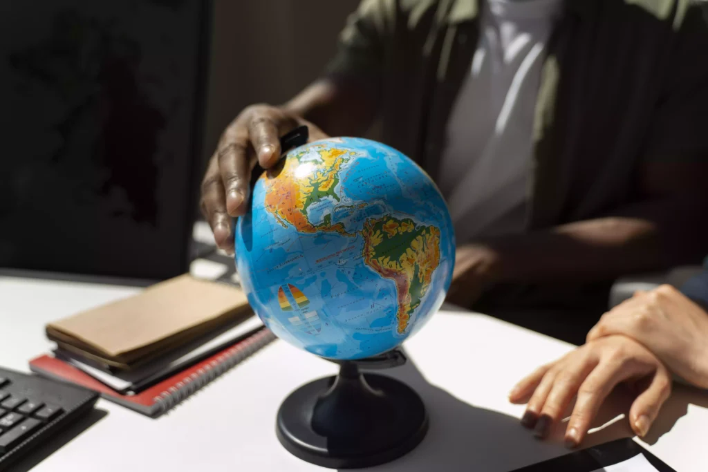 Person pointing at a globe in a study environment, representing international exchange planning at Fredericton Christian Academy.