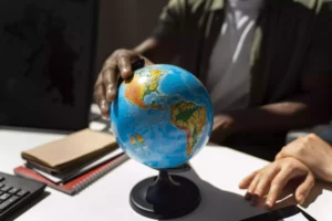 Pessoa apontando para um globo terrestre em ambiente de estudo, representando planejamento de intercâmbio internacional na Fredericton Christian Academy.