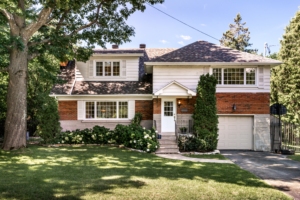 Casa típica canadense rodeada por árvores e jardim, representando o ambiente acolhedor de uma família anfitriã.