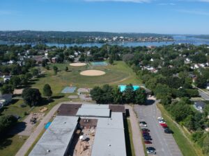 Vista aérea da cidade de Fredericton com campos esportivos, escola e o rio Saint John ao fundo.