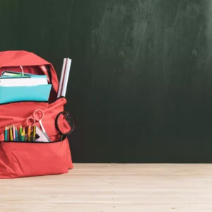 Mochila roja con útiles escolares que representan el entorno de aprendizaje de un High School Canadiense en una escuela cristiana de Fredericton.