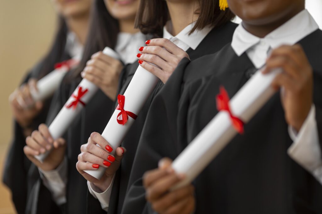 Students in gowns holding diplomas wrapped with red ribbons, symbolizing completion of academic courses at New Brunswick Community College.