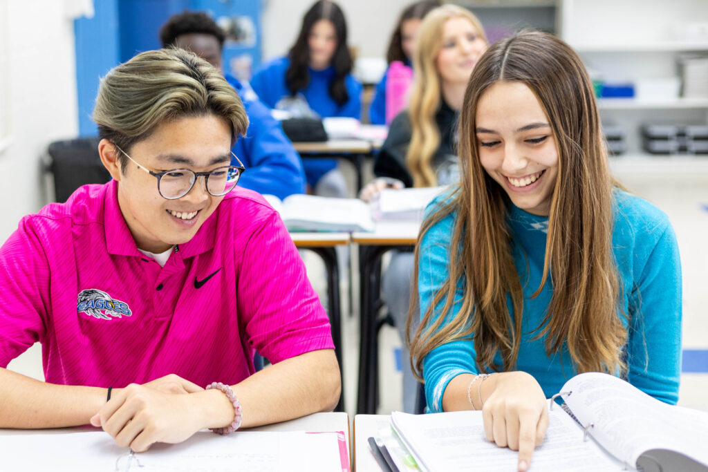 Two smiling students studying together in the classroom, symbolizing collaboration on a study plan.