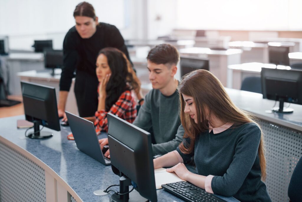 Estudantes em sala de informática programando em computadores, representando a atividade extracurricular de programação na Fredericton Christian Academy.