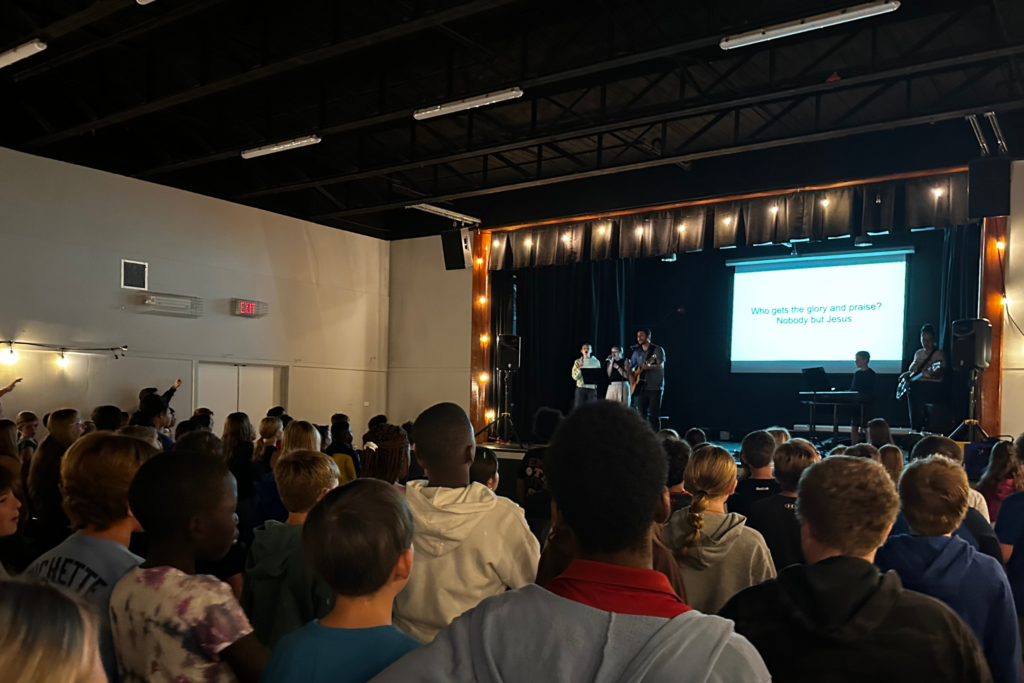 Students participating in a musical performance with Christian message in a school auditorium, as part of an educational project at the Fredericton Christian Academy.