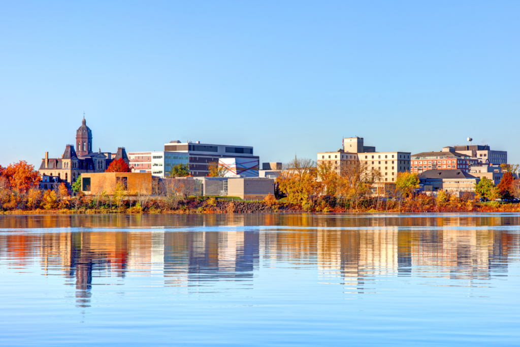 Vista da cidade de Saint Andrews, Canadá, com construções históricas e árvores em tons outonais refletidas no rio.
