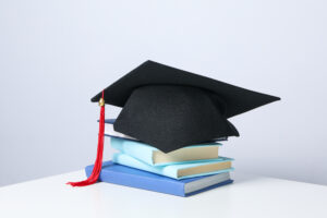 Capelo de formatura sobre pilha de livros, simbolizando educação e graduação na Simon Fraser University.