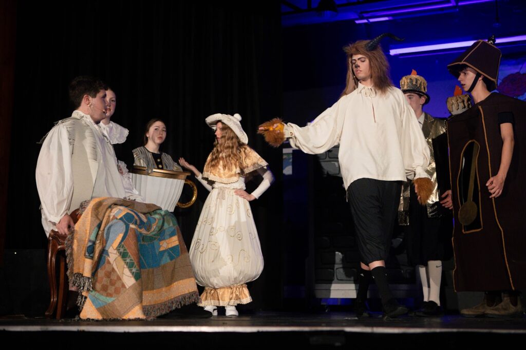 Estudantes caracterizados como personagens de conto de fadas durante apresentação teatral escolar, demonstrando expressão e envolvimento artístico.
