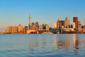 Vista panorâmica de Toronto ao entardecer, com a CN Tower e prédios refletidos na água, representando um dos principais destinos educacionais no Canadá.