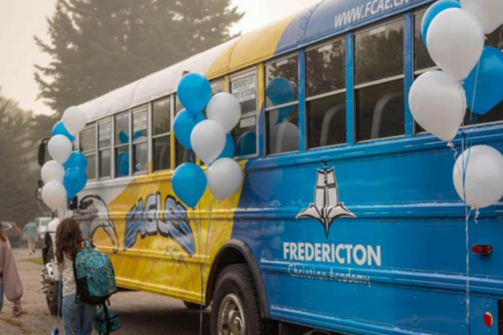 Fredericton school bus Christian Academy decorated with blue and white balloons, representing the school transportation service for students.