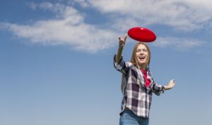 Estudante se divertindo ao jogar frisbee em um campo aberto, representando a prática de Ultimate Frisbee na Fredericton Christian Academy.