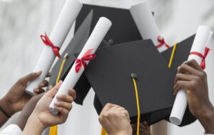 Mãos de estudantes segurando diplomas e capelos de formatura, simbolizando a conquista acadêmica na Universidade de New Brunswick.