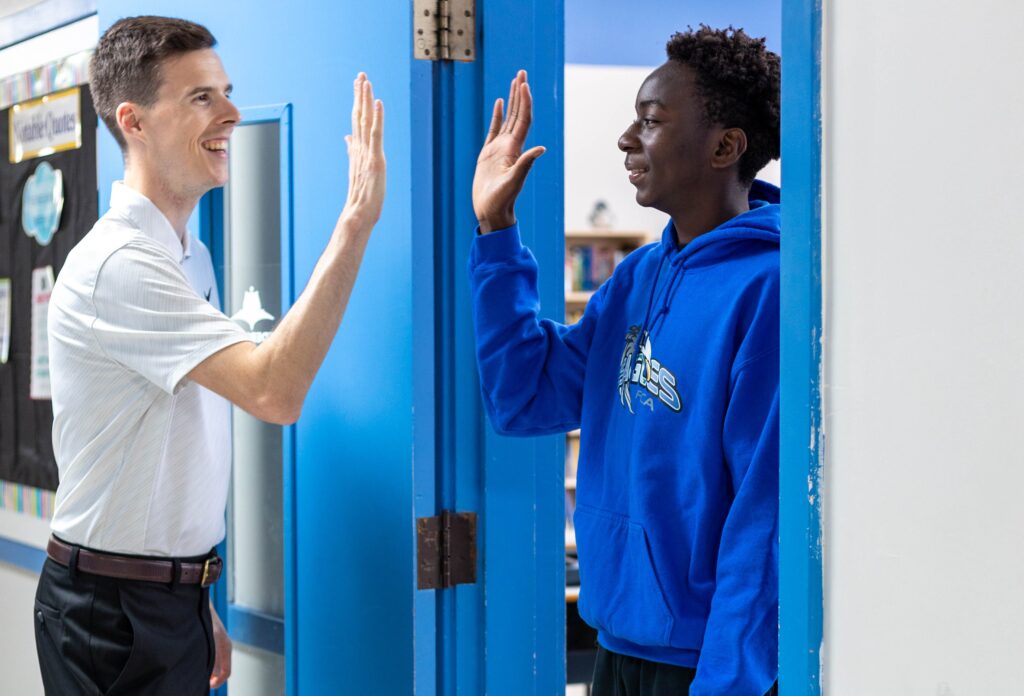 Teacher greeting student from Fredericton Christian Academy in the school hallway, representing close and individualized academic support.