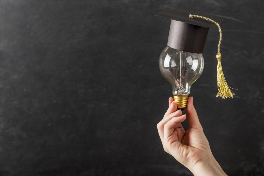 Hand holding a lamp with graduation cap symbolizing ideas and knowledge in higher education.