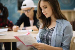 Pessoa preenchendo folha de respostas do teste GMAT com lápis, focada na prova.