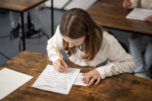 Aluna escrevendo prova do SAT em sala de aula, simbolizando preparação para ensino superior.