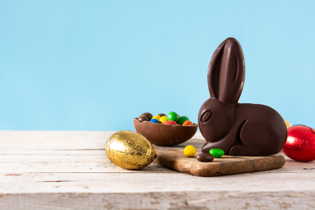 Coelho de chocolate com ovos coloridos representando as Easter Break (férias de Páscoa)