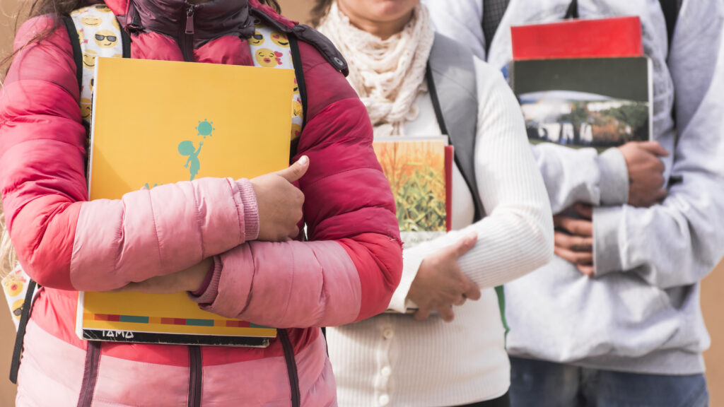 Students holding books and notebooks close to their bodies