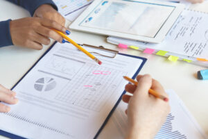 Mãos de estudantes analisando gráficos e dados de relatório escolar